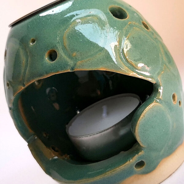 Brûle résine en grès émaillé naturel ton vert celadon, forme ronde recouvert de feuilles et troué partiellement . A l'intérieur se trouve une bougie chauffe-plat et au dessus, une grille (toujours fournie) permettant de déposer quelques grains de résines. Permet de parfumer un lieu, ou de le nettoyer des mauvaises énergies stagnantes.