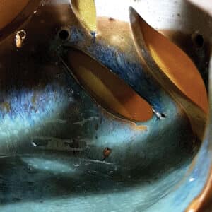 Détail. Brule-résine en terre de grés, émaillé bicolore, transparent et bleu-vert, décor de flamme. A l'intérieur se trouve une bougie chauffe-plat et au dessus, une grille permettant de déposer quelques grains de résines. Permet de parfumer un lieu, ou de le nettoyer des mauvaises énergies stagnantes.