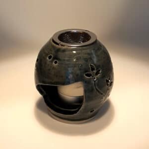Brûle résine en grès émaillé naturel, ton bleu, forme ronde décorée de fleurs. A l'intérieur se trouve une bougie chauffe-plat et au dessus, une grille permettant de déposer quelques grains de résines. Permet de parfumer un lieu, ou de le nettoyer des mauvaises énergies stagnantes.
