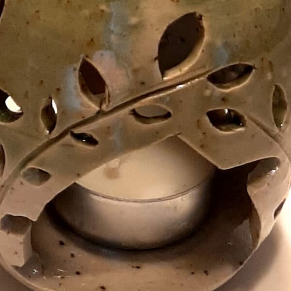 Détail. Brule-résine en terre de grés, émaillé bicolore, transparent et vert, décor de fleurs. A l'intérieur se trouve une bougie chauffe-plat et au dessus, une grille permettant de déposer quelques grains de résines. Permet de parfumer un lieu, ou de le nettoyer des mauvaises énergies stagnantes.