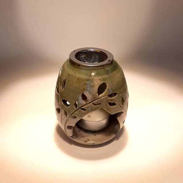 Brule-résine en terre de grés, émaillé bicolore, transparent et vert, décor de fleurs. A l'intérieur se trouve une bougie chauffe-plat et au dessus, une grille permettant de déposer quelques grains de résines. Permet de parfumer un lieu, ou de le nettoyer des mauvaises énergies stagnantes.