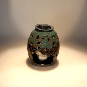 Brule-résine en terre de grés, émaillé bicolore, noir et turquoise, décor de fleurs. A l'intérieur se trouve une bougie chauffe-plat et au dessus, une grille permettant de déposer quelques grains de résines. Permet de parfumer un lieu, ou de le nettoyer des mauvaises énergies stagnantes.