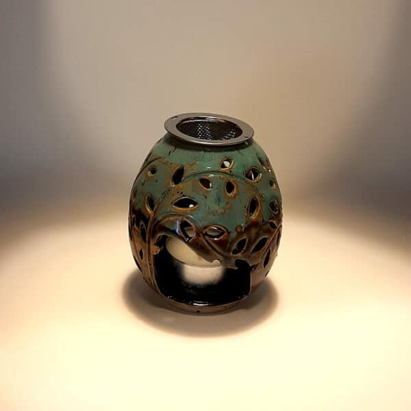 Brule-résine en terre de grés, émaillé bicolore, noir et turquoise, décor de fleurs. A l'intérieur se trouve une bougie chauffe-plat et au dessus, une grille permettant de déposer quelques grains de résines. Permet de parfumer un lieu, ou de le nettoyer des mauvaises énergies stagnantes.