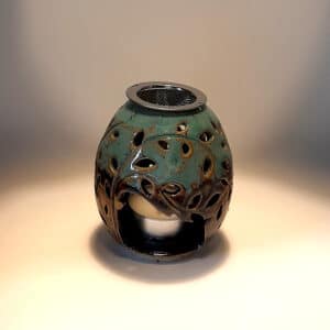 Brule-résine en terre de grés, émaillé bicolore, noir et turquoise, décor de fleurs. A l'intérieur se trouve une bougie chauffe-plat et au dessus, une grille permettant de déposer quelques grains de résines. Permet de parfumer un lieu, ou de le nettoyer des mauvaises énergies stagnantes.