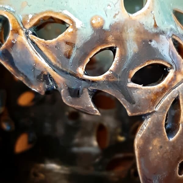 Détail. Brule-résine en terre de grés, émaillé bicolore, noir et turquoise, décor de fleurs. A l'intérieur se trouve une bougie chauffe-plat et au dessus, une grille permettant de déposer quelques grains de résines. Permet de parfumer un lieu, ou de le nettoyer des mauvaises énergies stagnantes.