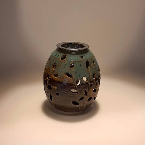 Brule-résine en terre de grés, émaillé bicolore, noir et turquoise, décor de fleurs. A l'intérieur se trouve une bougie chauffe-plat et au dessus, une grille permettant de déposer quelques grains de résines. Permet de parfumer un lieu, ou de le nettoyer des mauvaises énergies stagnantes.