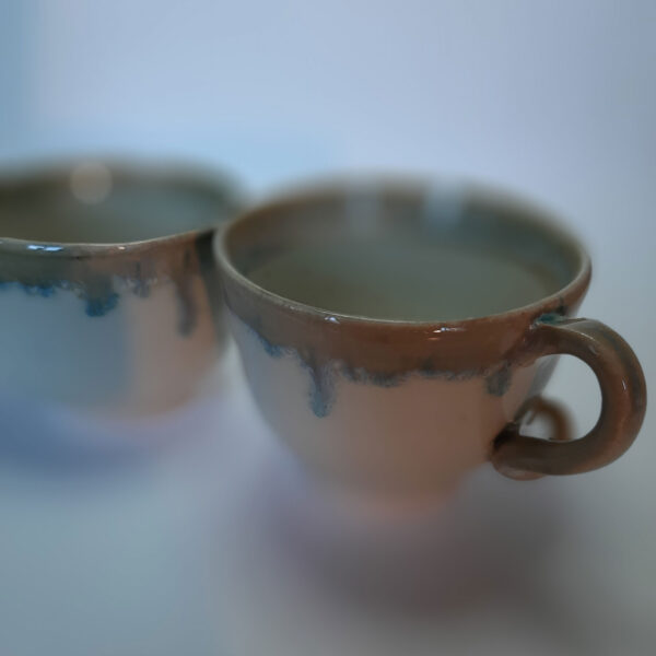 Tasses en duo, en grès blanc, cuisson électrique. Recouverte d'un émail blanc et d'un autre émail sur les bords ce qui créé une réaction chimique et nous fait découvrir un liseré comme le lichen dans des tons bleutés.