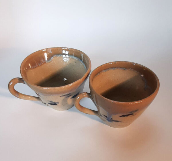 Tasses en duo, en grès blanc, cuisson électrique. Recouverte d'un émail blanc et d'un autre émail sur les bords ce qui créé une réaction chimique et nous fait découvrir un liseré comme le lichen dans des tons bleutés.