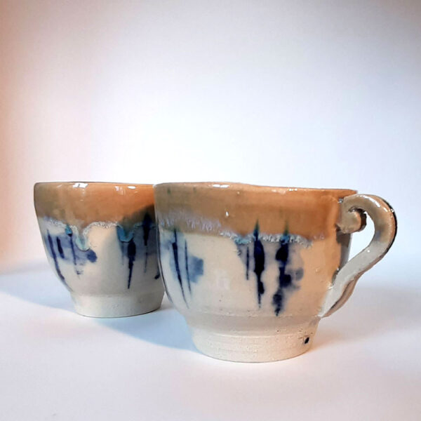 Tasses en duo, en grès blanc, cuisson électrique. Recouverte d'un émail blanc et d'un autre émail sur les bords ce qui créé une réaction chimique et nous fait découvrir un liseré comme le lichen dans des tons bleutés. Motifs design.