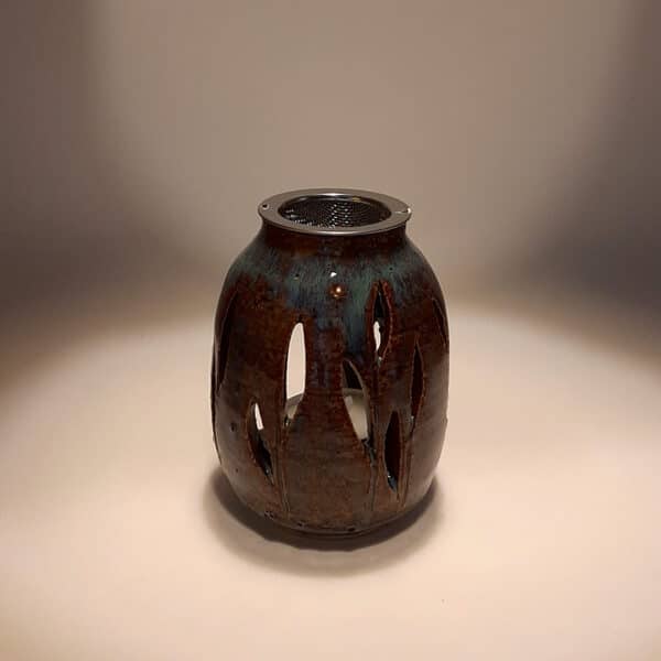 Brule-résine en terre de grés, émaillé marron/bleu, décor de feuille. A l'intérieur se trouve une bougie chauffe-plat et au dessus, une grille permettant de déposer quelques grains de résines. Permet de parfumer un lieu, ou de le nettoyer des mauvaises énergies stagnantes.