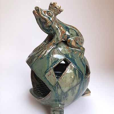 Encensoir pour charbon en forme ronde surplombée d'une grenouille. Grès dans les tons verts amandes et plus prononcés.