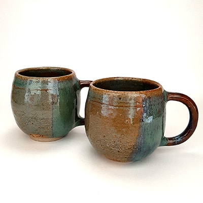 Duo de tasses avec anse en grès émaillé. Formes rondes en 2 couleurs marron et bleu. Tasses pour café.