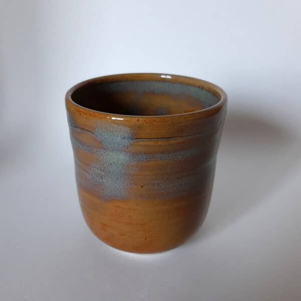 Jolie tasse en grès recouverte d'un émail couleur caramel avec bandeau dans des tons turquoises. Idéal pour un bon café. Compatible au lave-vaisselle.