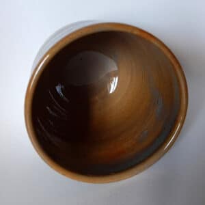Intérieur. Jolie tasse en grès recouverte d'un émail couleur caramel avec bandeau dans des tons turquoises. Idéal pour un bon café. Compatible au lave-vaisselle.