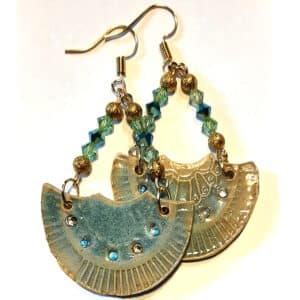 Détail de boucles d'oreilles accompagnées de perles cristal. Forme éventail, monture métal doré.