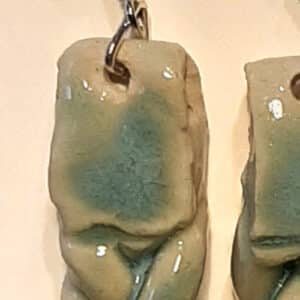 Détail de boucles d'oreilles en forme de tresse en grés émaillé. Monture métal argenté.