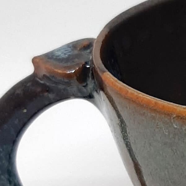 Détail de la poignée. Tasse à café en grés émaillé de la collection "Eclipse". Mélange de deux émaux qui offre la 3e couleur.