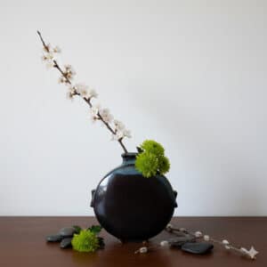 Vue face noire dans une ambiance Ikebana. Dans la collection des "Elégantes", vase en grés émaillé Eclipse. Céramique aux 2 couleurs turquoise et noir avec effet de matière.
