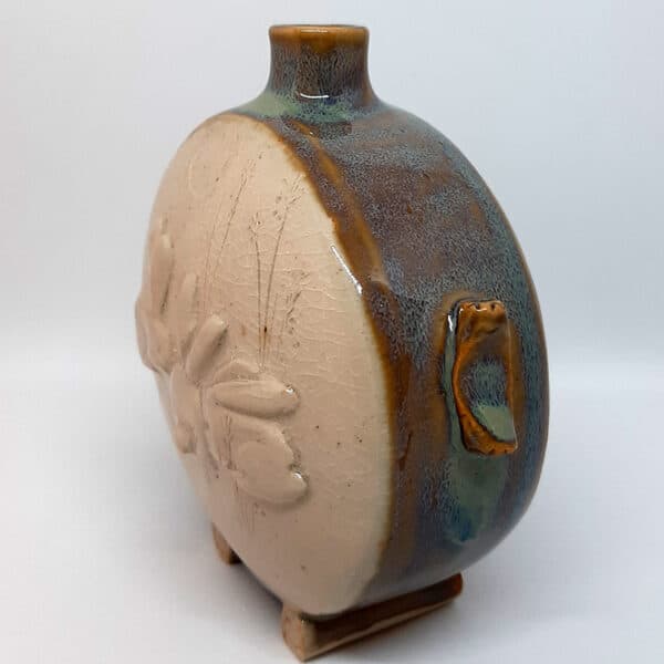 Vue de profil. Dans la collection des "Elégantes", vase en grés émaillé Azurite. Céramique aux 2 couleurs bleu et marron sur l'arrière, au dos et côté avec effet de matière.