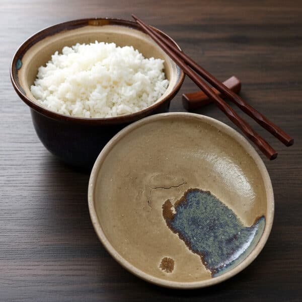 Pot à riz en grés émaillé Azurite avec couvercle en grès. Mise en situation avec du riz comme ingrédient. Céramique aux 2 couleurs bleu et marron avec effet de matière.