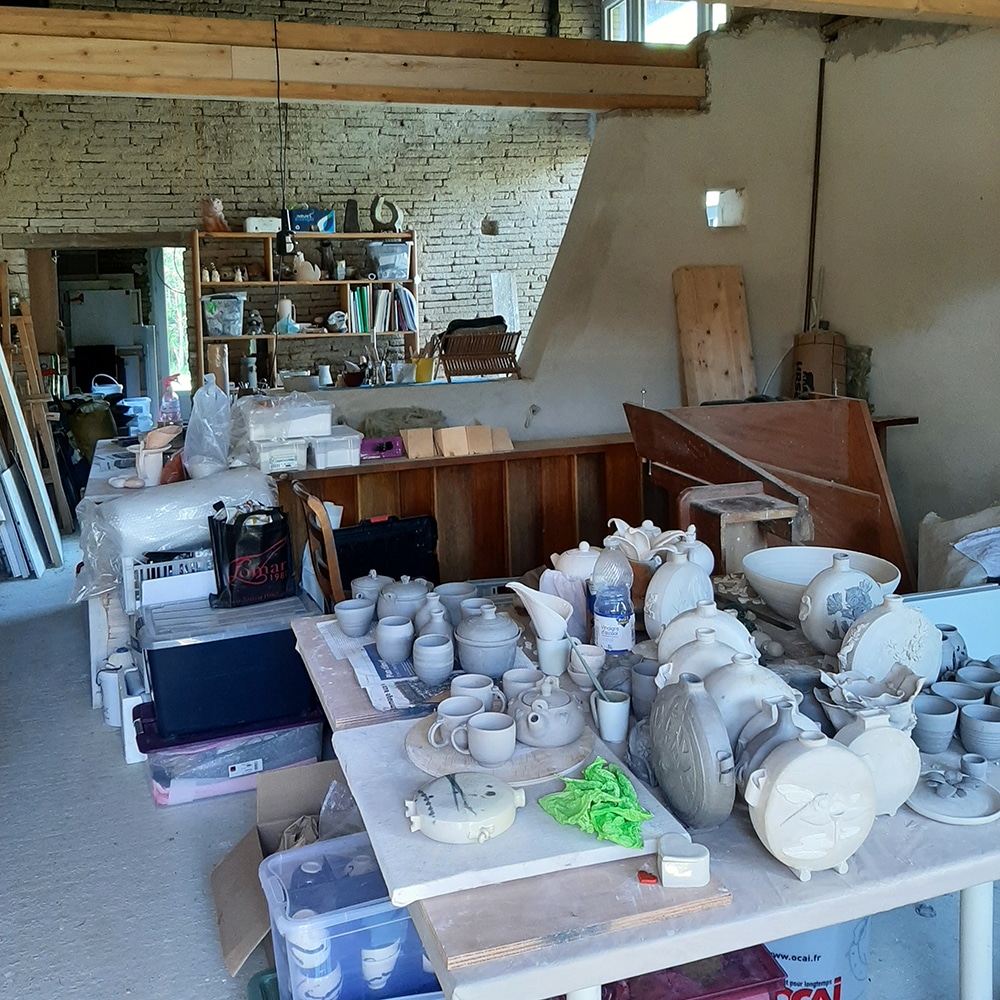 Intérieur de l'atelier à COX. Sur une table la fabrication prête à être enfournée.